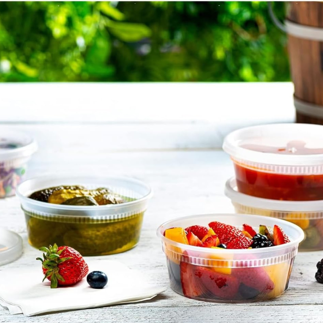 Containers of fruit salad and other food items on a table with a blurred green background